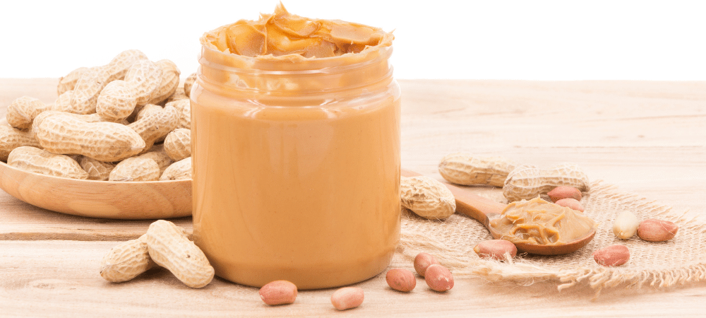 peanut butter in a jar on a table with peanuts