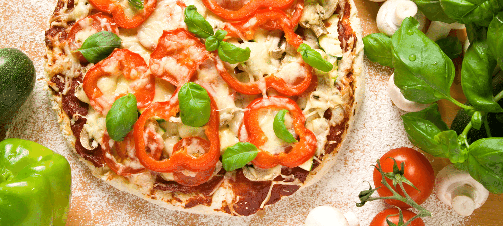 pizza topped with mushrooms, bell peppers, tomatoes, and fresh basil leaves