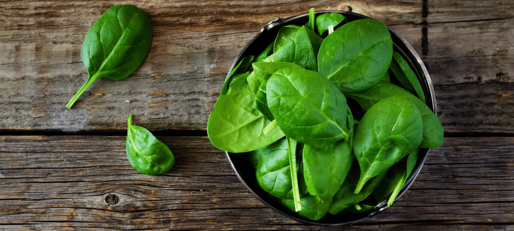 bowl of spinach on a wooden table