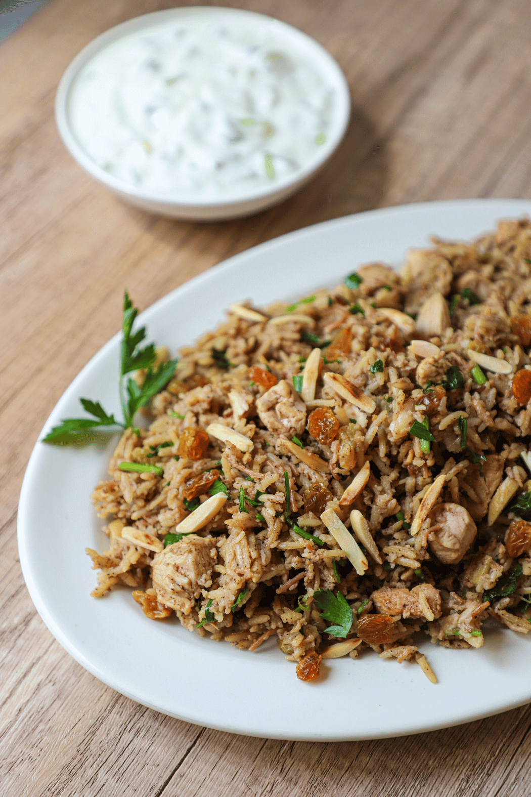 Chicken Biryani on a plate with yogurt sauce in the background