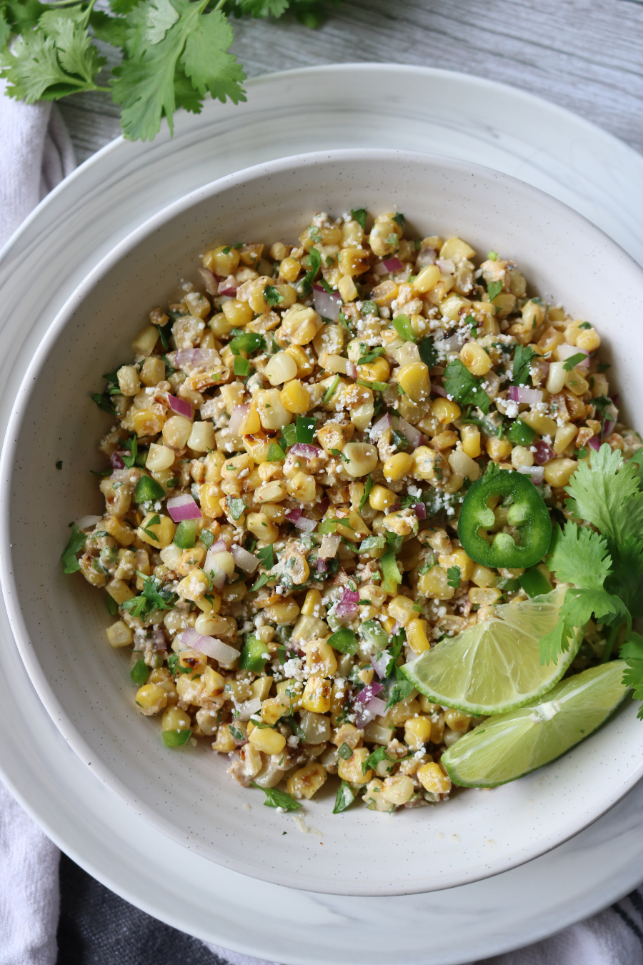 Elote salad in a bowl with lime and cilantro