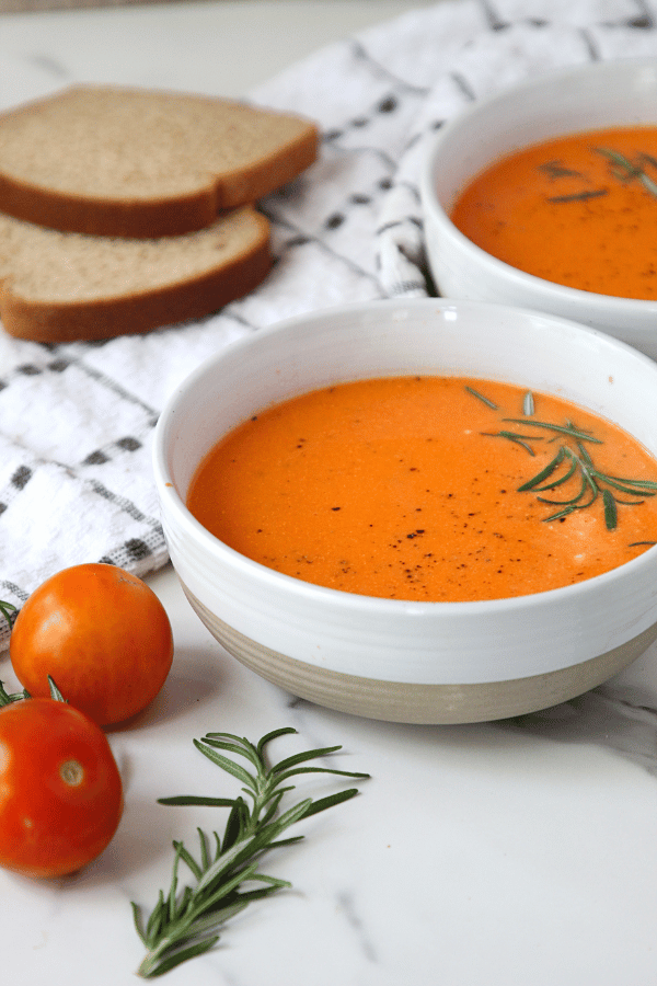 Roasted feta soup in a bowl with whole wheat bread in a background