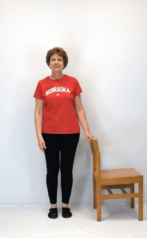 An individual modeling how to do a same arm and leg raise exercise.