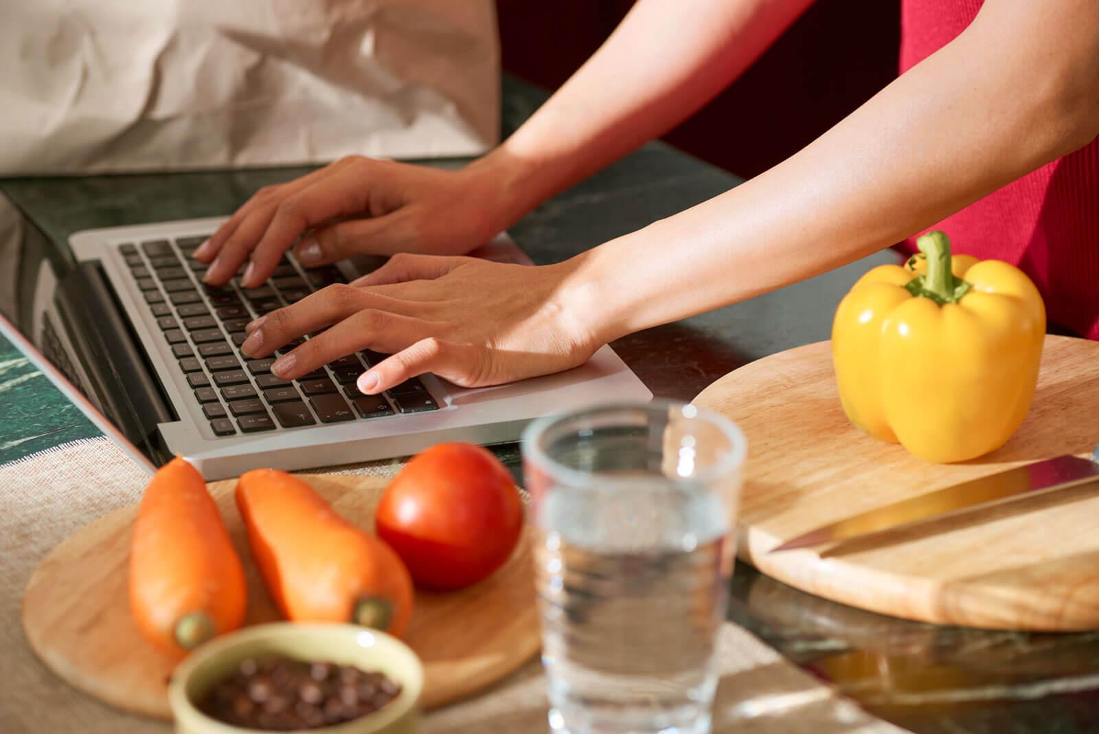 Woman typing on a laptop in the kitchen.