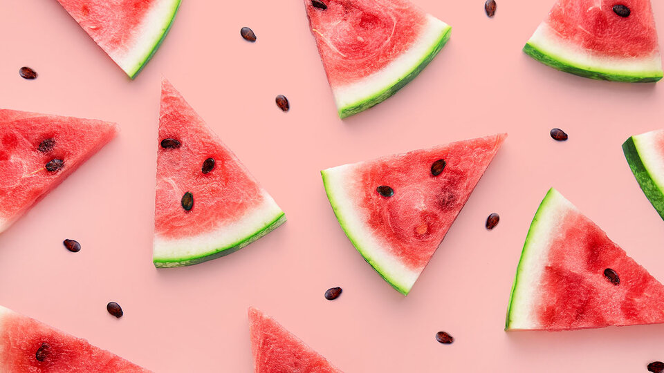 Watermelon slices and seeds scattered on a pink background.