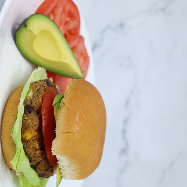 bean burger on a plate served with avocado and tomatoes