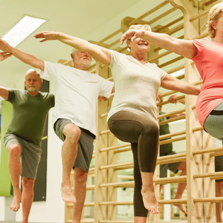 group of seniors doing balance exercise on one leg