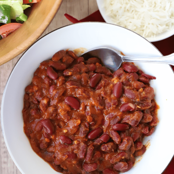 bean stew in a bowl, rice and salad on the side