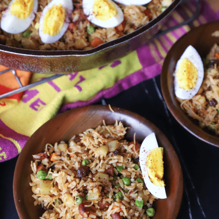 Biryani with eggs in 2 bowls and a skillet