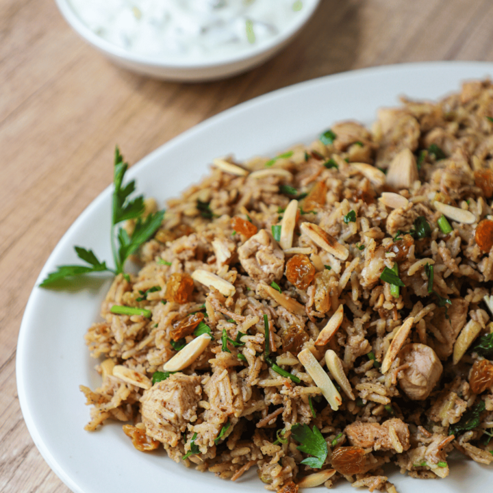 Chicken Biryani on a plate with yogurt sauce in the background