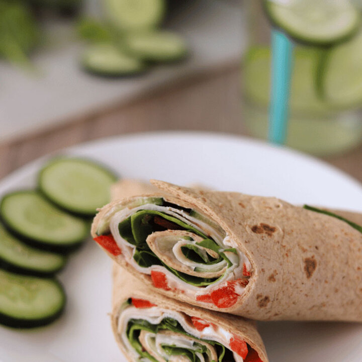 Cucumber wrap on a plate with sliced cucumbers.