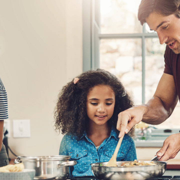 family of four cooking together in a kitchen