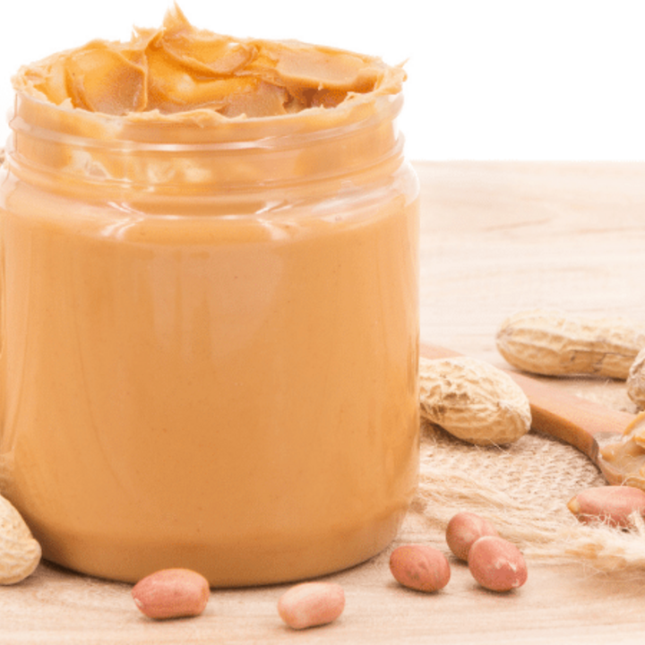 peanut butter in a jar on a table with peanuts