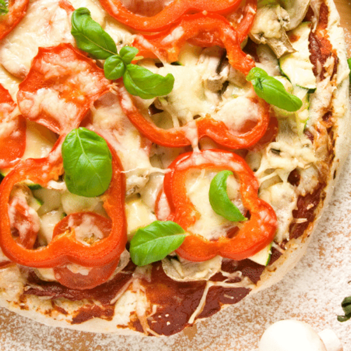 pizza topped with mushrooms, bell peppers, tomatoes, and fresh basil leaves