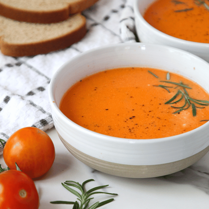 Roasted feta soup in a bowl with whole wheat bread in a background