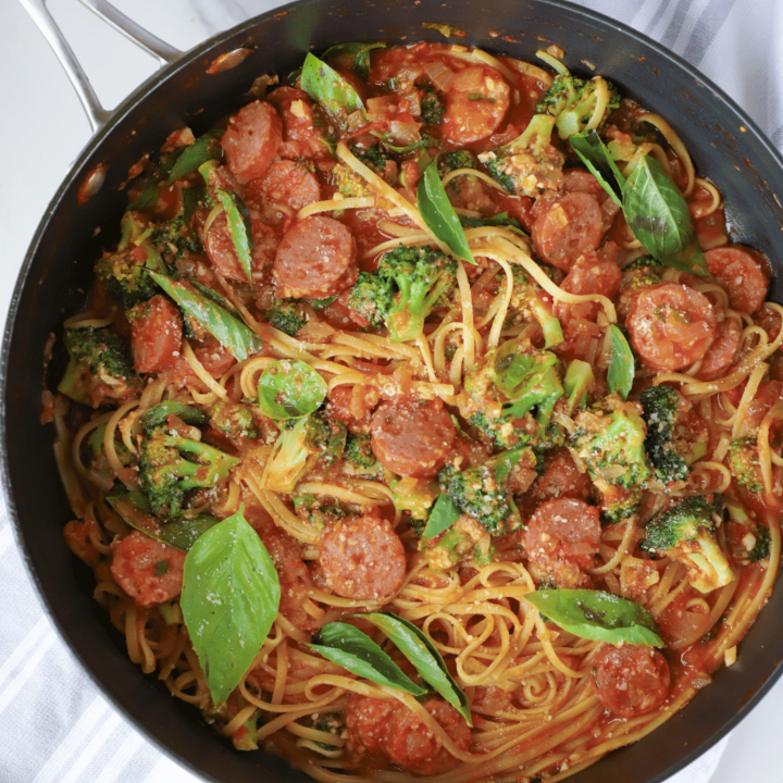 Pasta with sausage, broccoli and fresh basil in a skillet