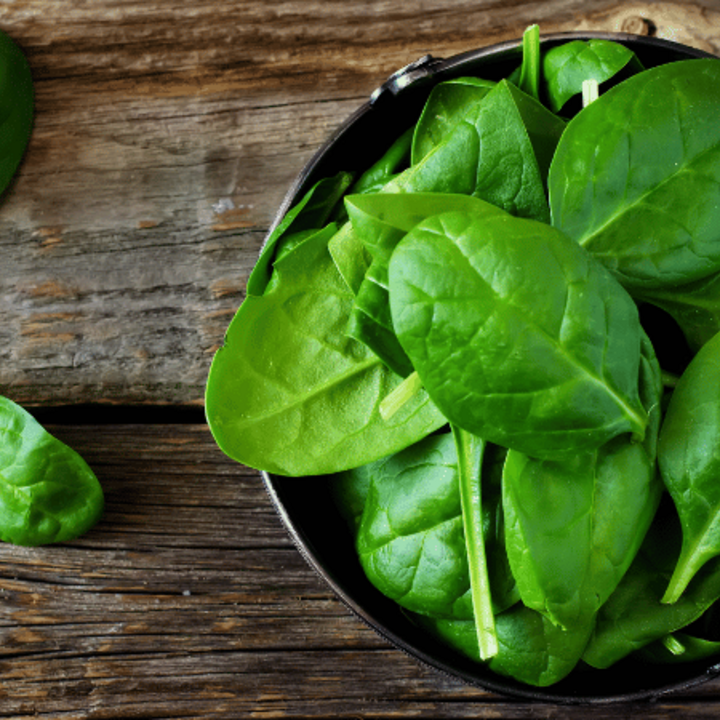 bowl of spinach on a wooden table