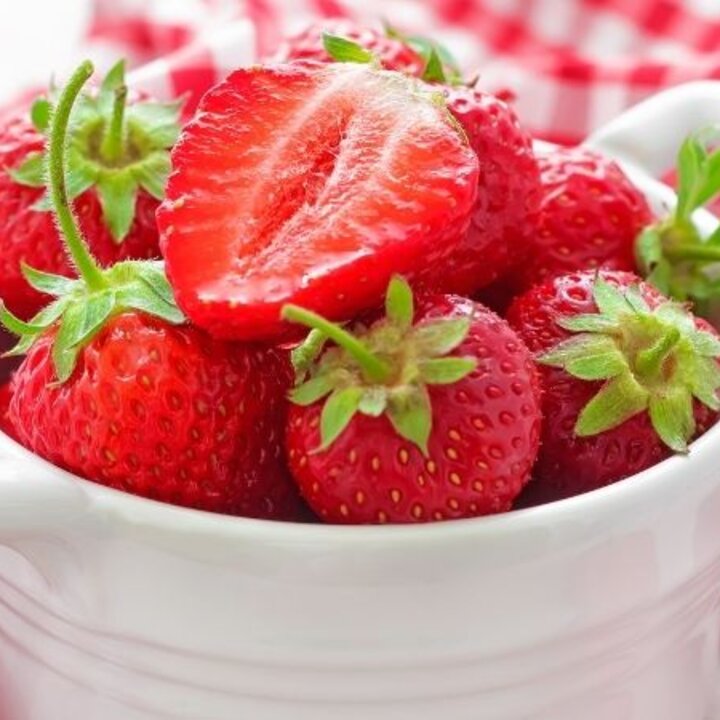 strawberries in a white bowl with a checkered tablecloth