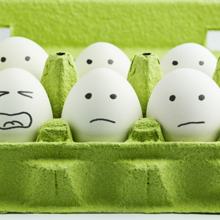 variety of stressed faces drawn on eggs