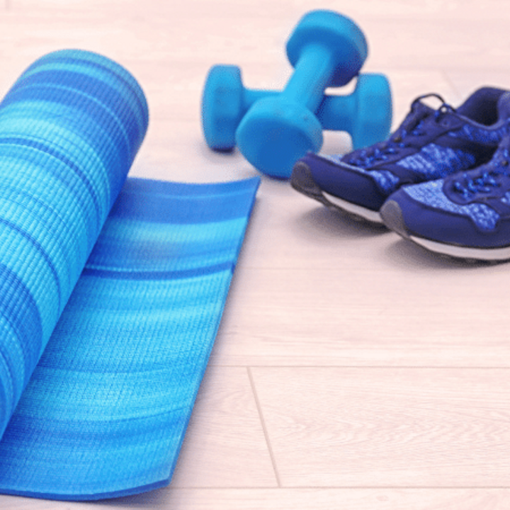 yoga mat, weights, and tennis shoes on a wooden floor