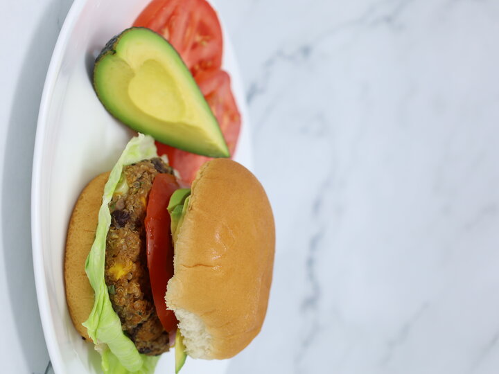 bean burger on a plate served with avocado and tomatoes