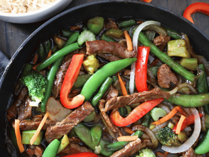 stir fry in a skillet with rice on the side