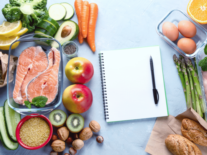 pen and paper surrounded by foods to help plan meals on a budget