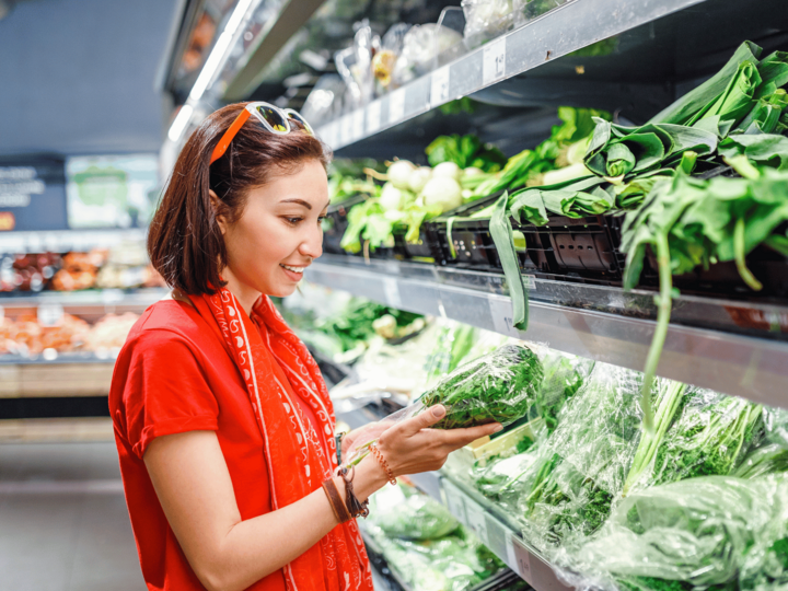 woman looking at salad greens in a grocery store