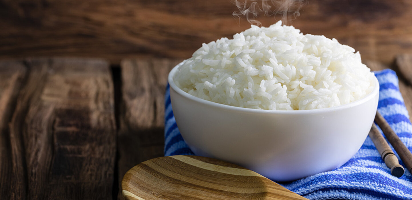 cooked rice in a whole bowl with a wooden spoon and blue towel