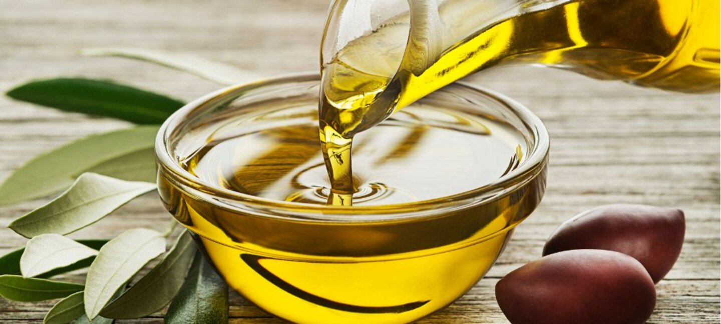 olive oil being poured into a glass bowl