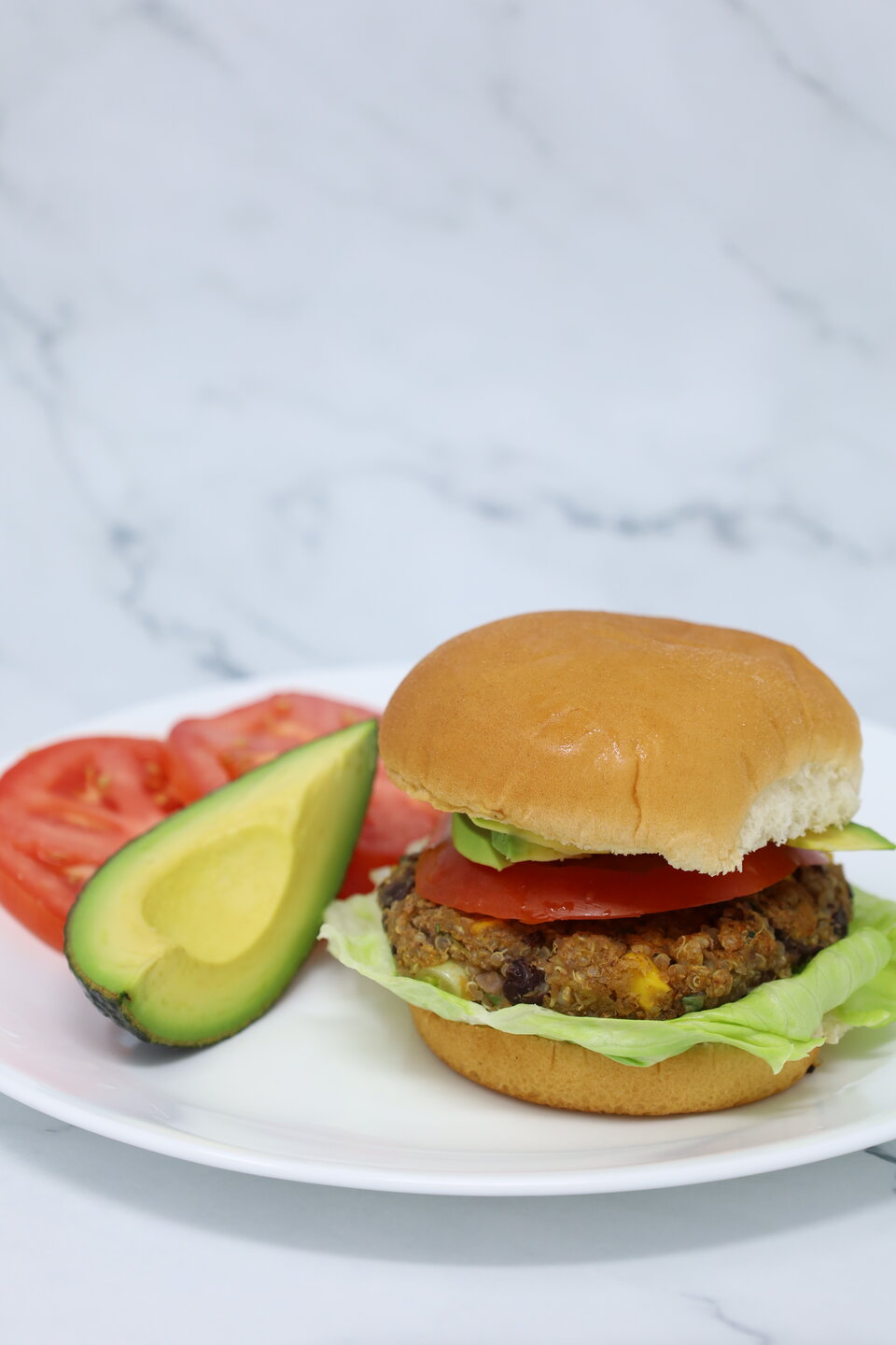 bean burger on a plate served with avocado and tomatoes