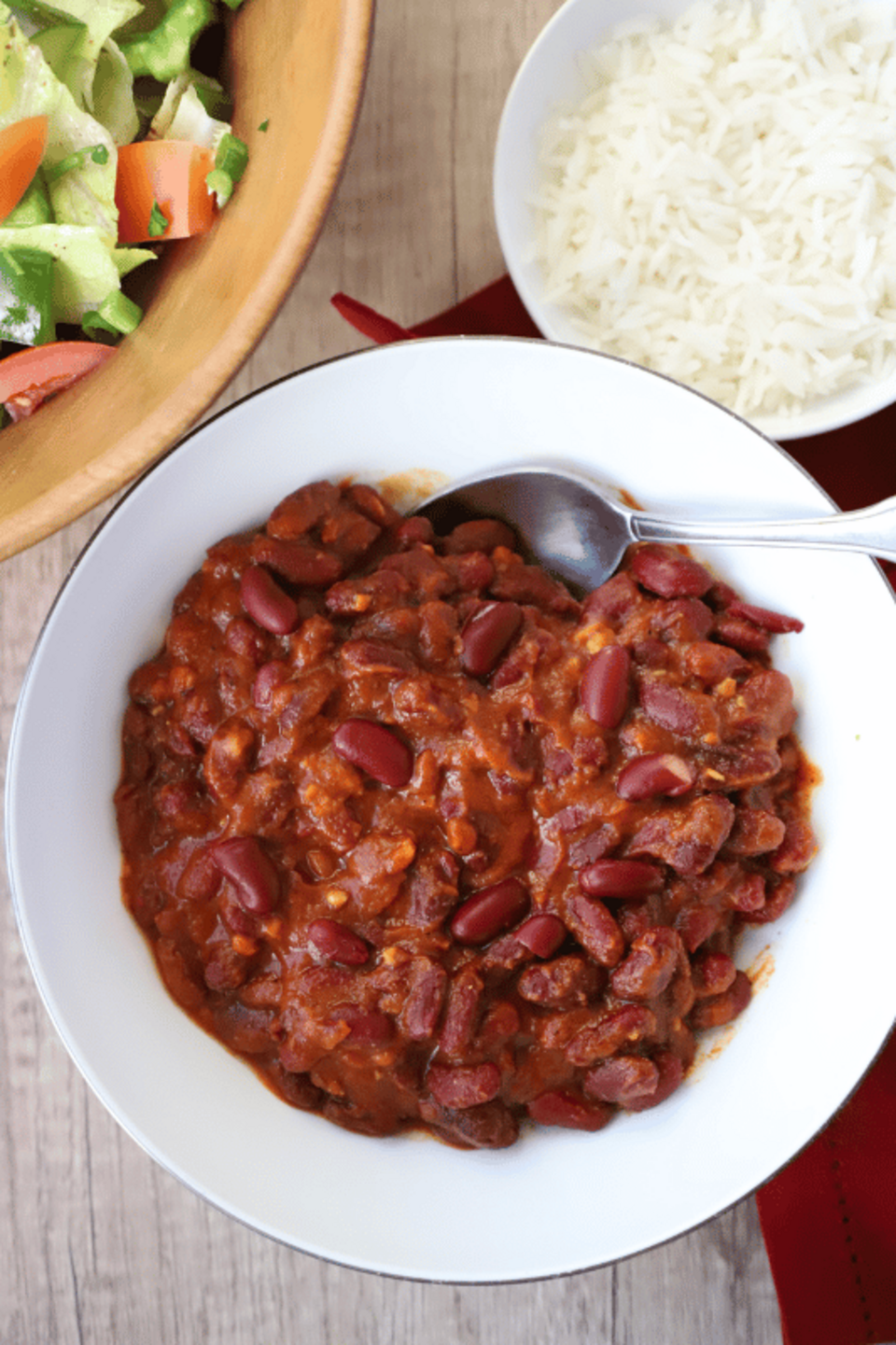 bean stew in a bowl, rice and salad on the side