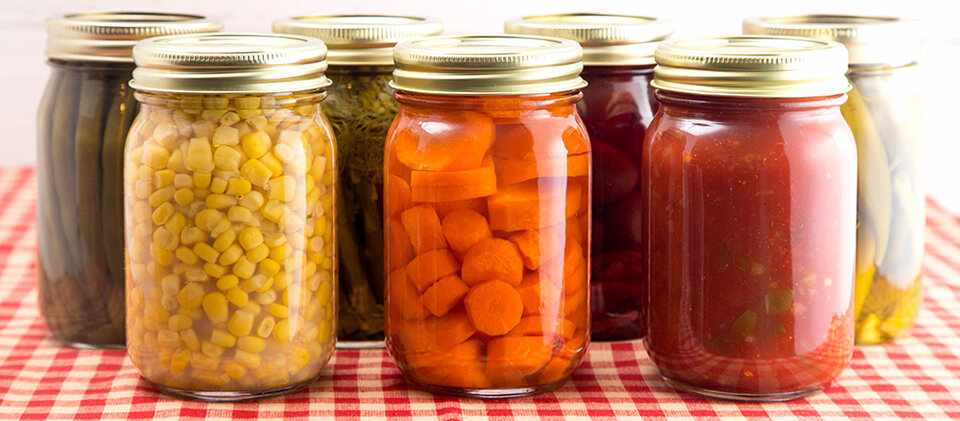 canning jars filled with food including corn, carrots and tomatoes