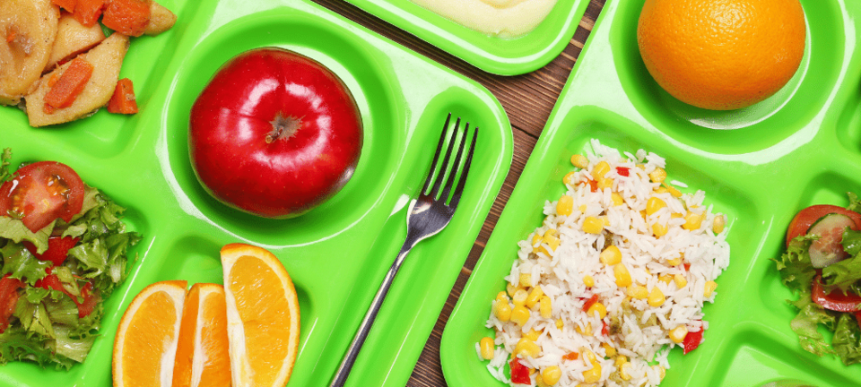 school lunch trays with fresh produce on table