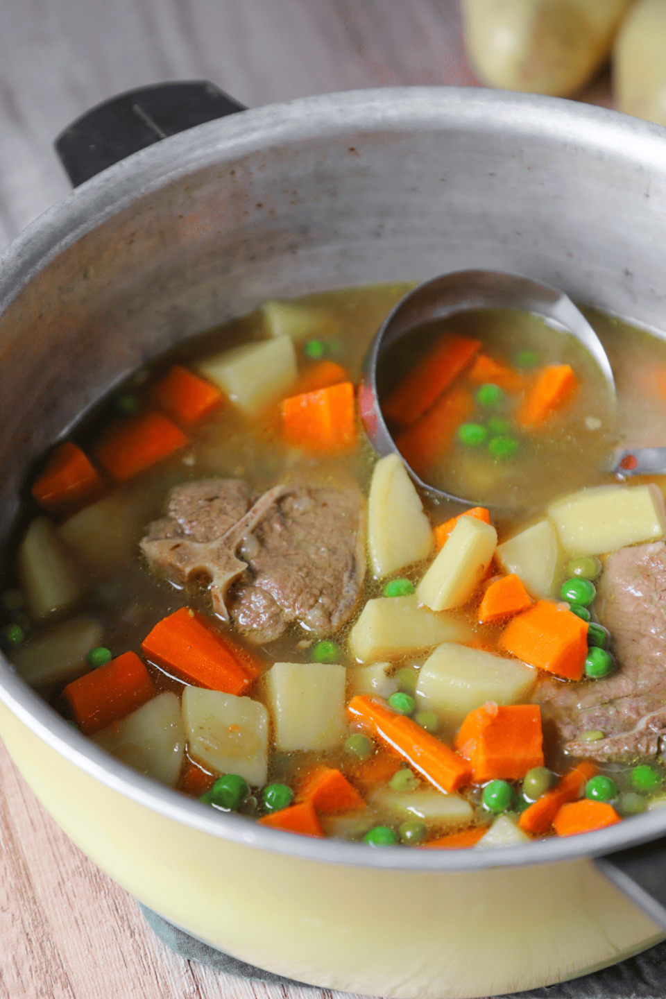 Soup in a pot with lamb, carrots, potatoes and peas