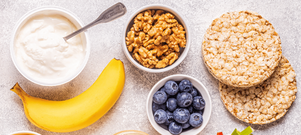 healthy snacks such as yogurt, banana, blueberries, walnuts, and rice cakes