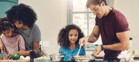 family of four cooking together in a kitchen