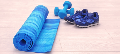 yoga mat, weights, and tennis shoes on a wooden floor