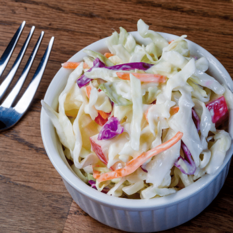 coleslaw in a white bowl with a fork