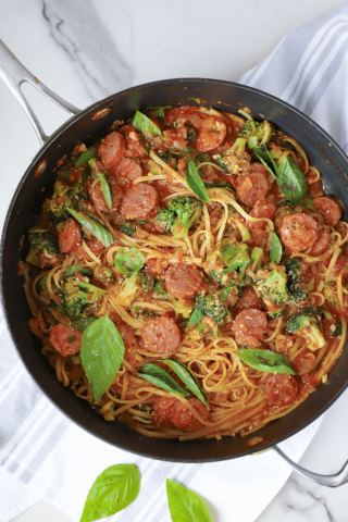 Pasta with sausage, broccoli and fresh basil in a skillet